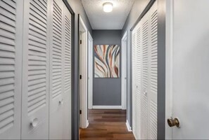 A hallway with lockers on both sides, a wooden floor, and a wall with abstract art. - Sleek & Peaceful Retreat at Bailey Court #1 (El Dorado)