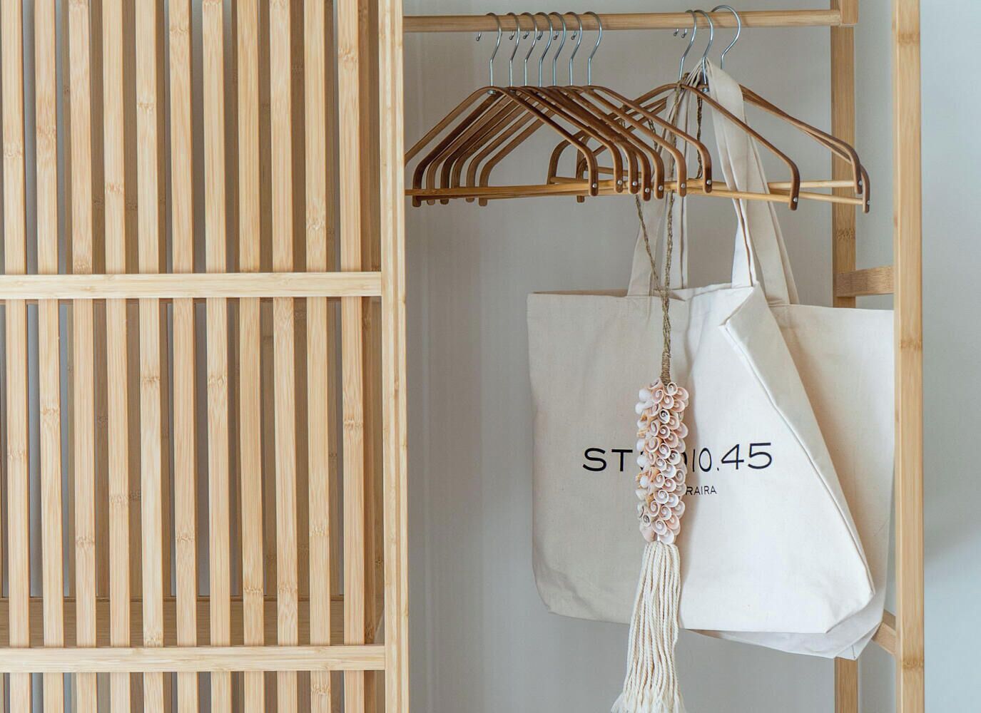 Une armoire en bois avec une tringle pour suspendre les vêtements, un sac blanc orné de motifs floraux et une étiquette avec du texte.