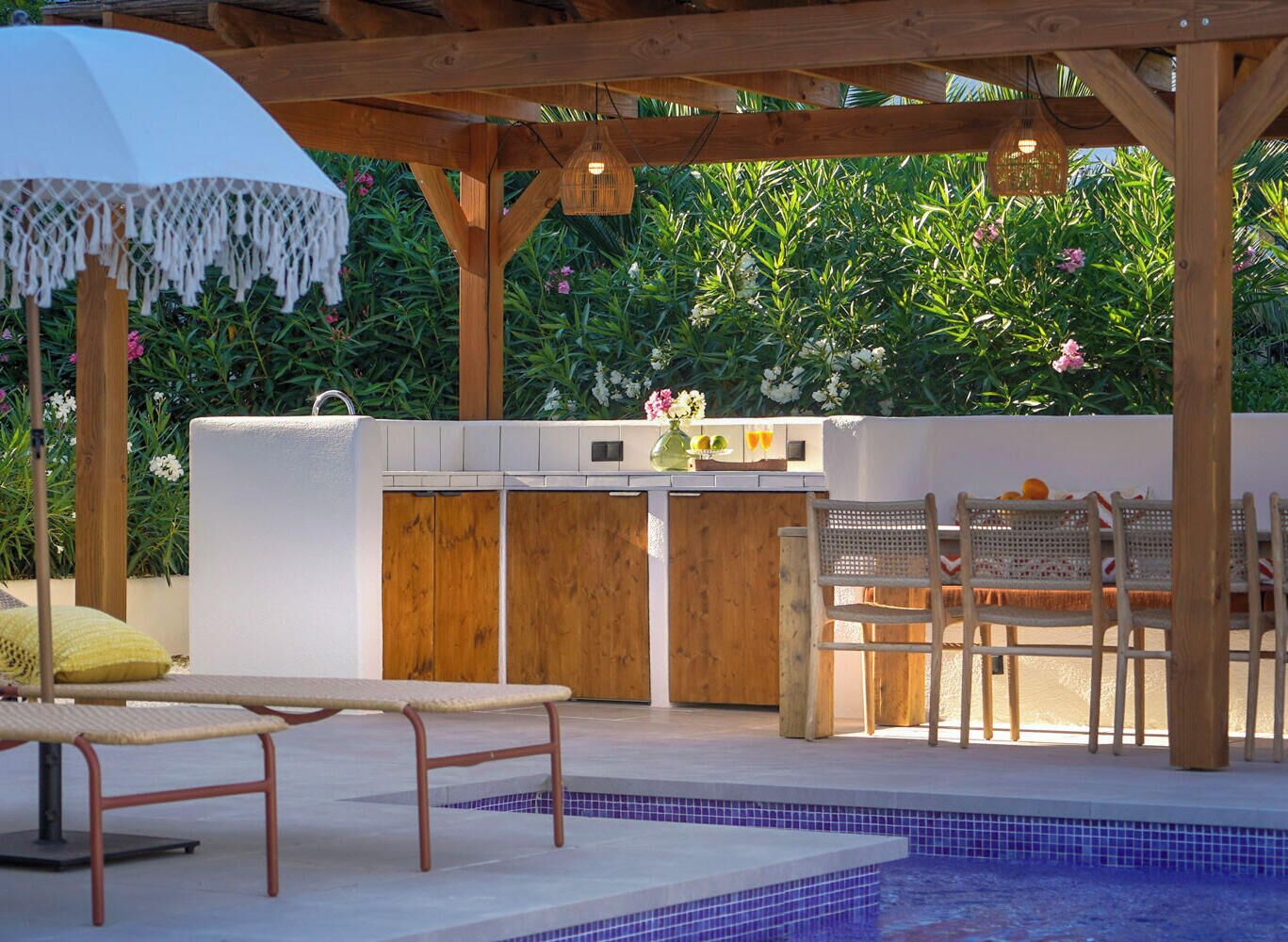An outdoor kitchen area with a pool, wooden deck, and seating.