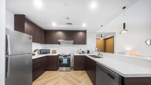 Una cocina moderna con electrodomésticos de acero inoxidable, armarios de madera y un suelo de madera en espiga.