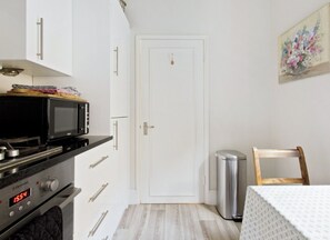 Une cuisine compacte équipée d’un four à micro-ondes, d’un four traditionnel et d’une horloge indiquant 15 h 54.