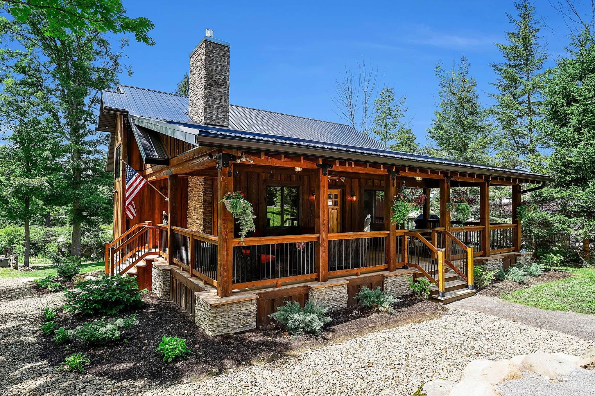 Un chalet doté d’une cheminée en pierre, d’une terrasse en bois et d’un porche abrité.