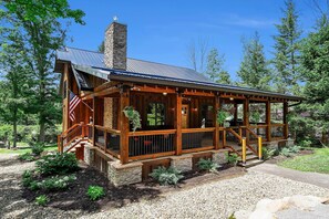 Un chalet doté d’une cheminée en pierre, d’une terrasse en bois et d’un porche abrité.