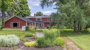 Ein rotes Haus mit Garten, weißem Zaun und einem gepflasterten Weg.