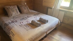 A neatly made bed with a patterned bedspread and two rolled towels.