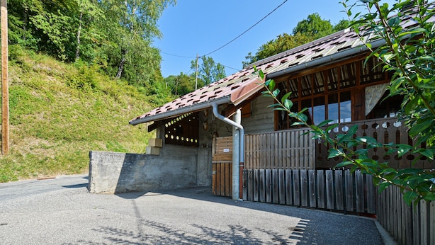 A rustic building with a sloped roof, a wooden gate, and a concrete wall.