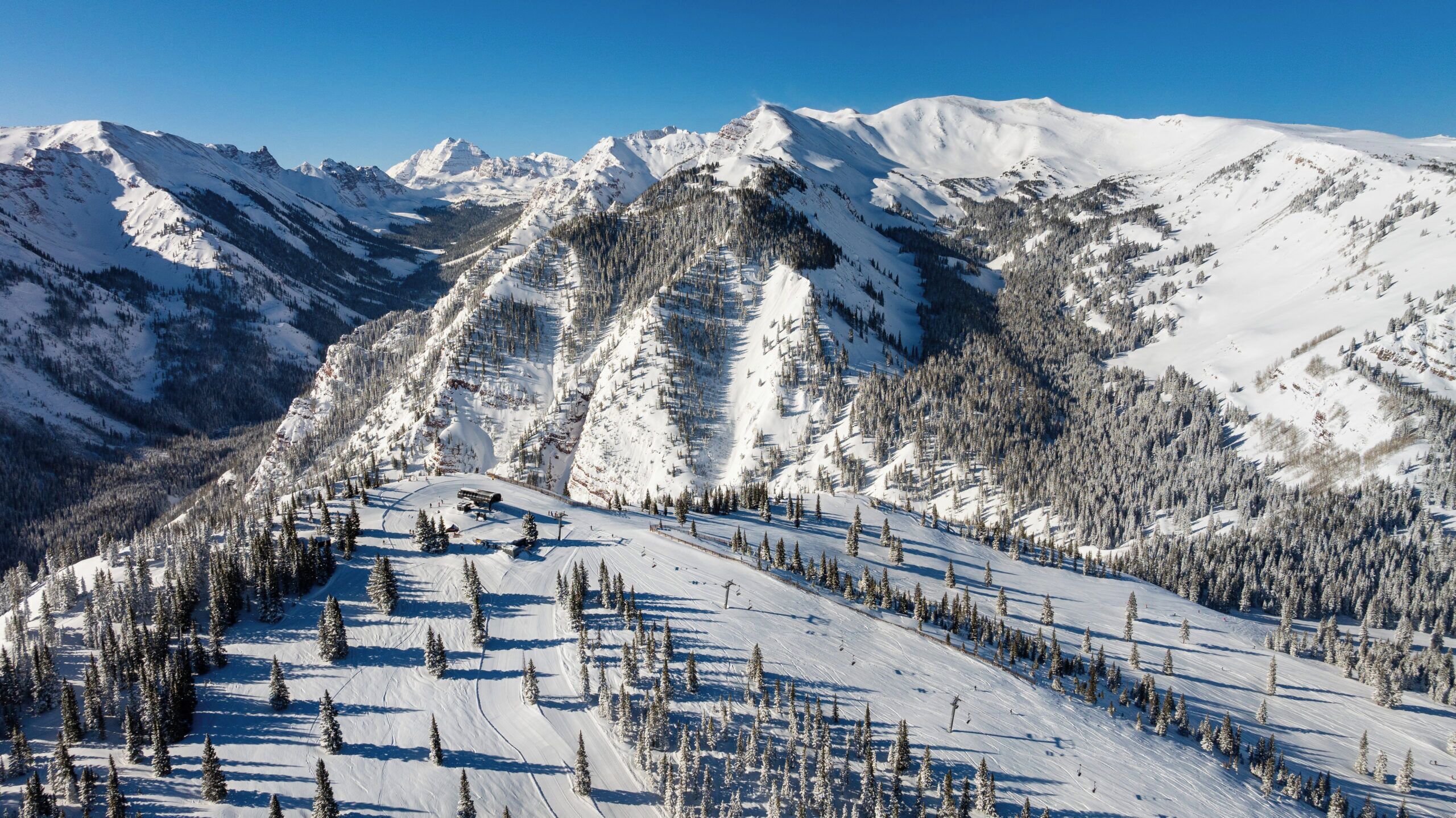 Eine verschneite Berglandschaft mit Skipisten und Bäumen.