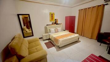 Ein Hotelzimmer mit Bett, Sofa, Schreibtisch, Spiegel und Kleiderschrank.