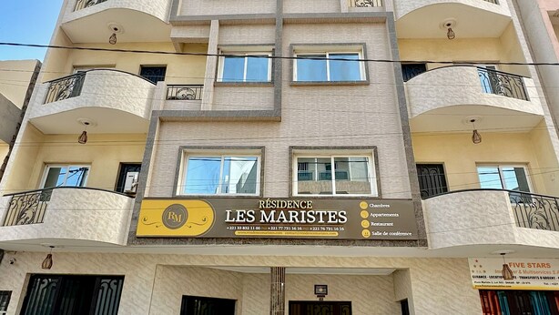 A multi-story building with a sign for 'RESIDENCE LES MARISTES' indicating amenities such as apartments, a restaurant, and a conference hall. - Residence Les Maristes (Dakar)