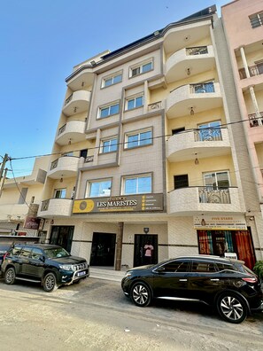 Un immeuble à plusieurs étages dont le rez-de-chaussée est affecté à des commerces, notamment un restaurant et un bureau de gestion immobilière.