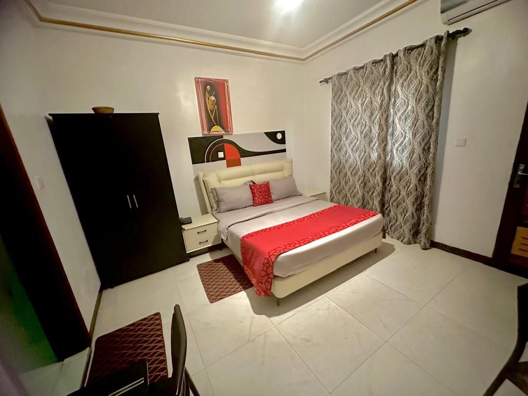 A bedroom with a bed, a nightstand, a wardrobe, and a painting on the wall.