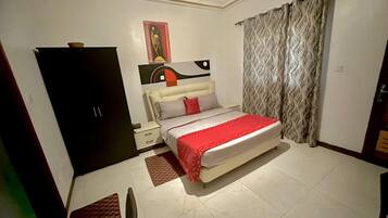 A bedroom with a bed, a nightstand, a wardrobe, and a painting on the wall.