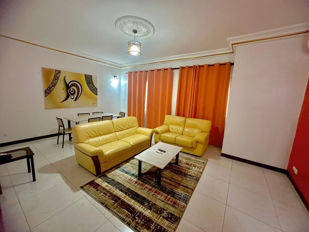 Una sala de estar con dos sofás amarillos, una mesa de centro y una alfombra estampada.