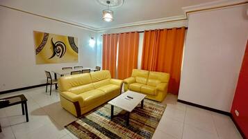 Una sala de estar con dos sofás amarillos, una mesa de centro y una alfombra estampada.