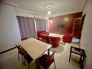 Un comedor con una mesa y sillas, un sofá rojo y un televisor en la pared.