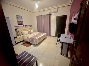 A bedroom with a bed, bedside table, and a desk with a chair.