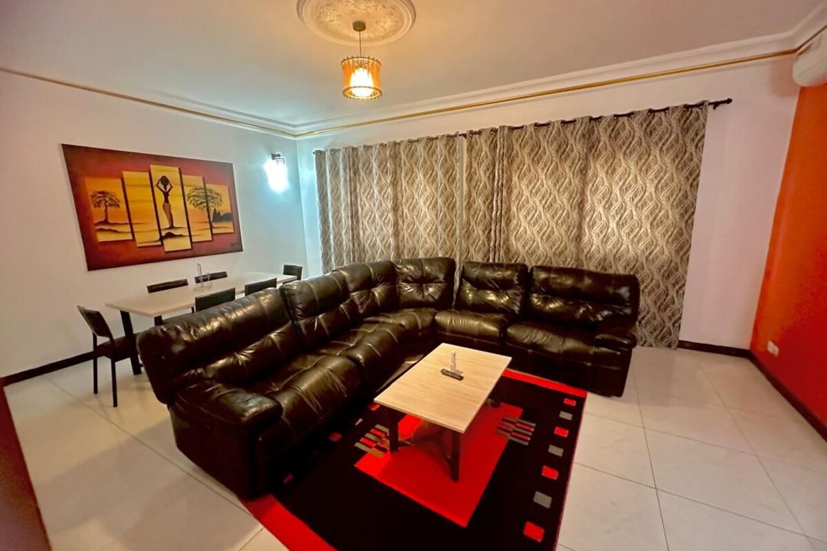 A living room with a sectional sofa, a coffee table, and a dining area with chairs.