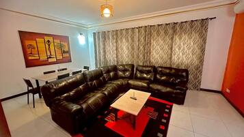 A living room with a sectional sofa, a coffee table, and a dining area with chairs.