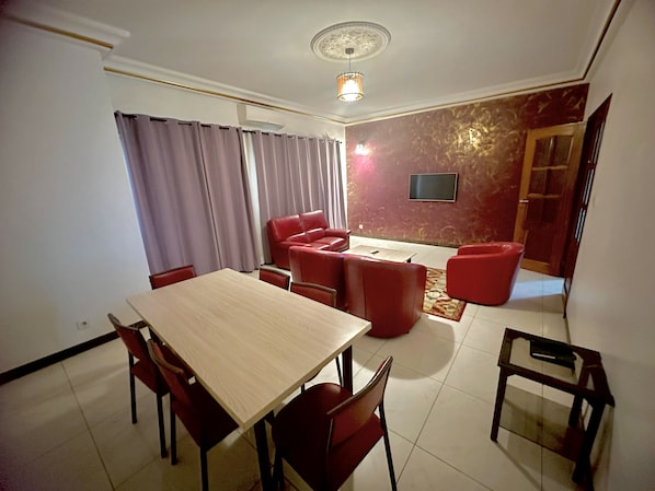 Un espace repas comprenant une table et des chaises, un canapé et un téléviseur fixé au mur.