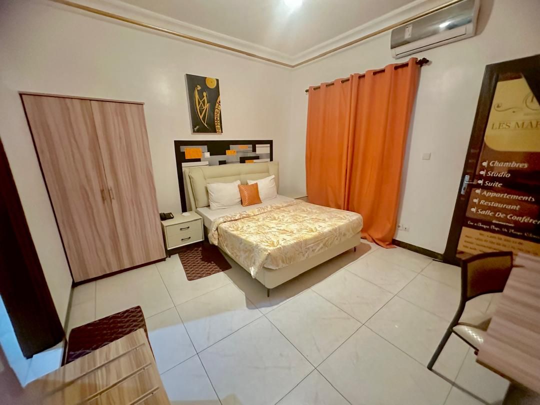 A hotel room with a bed, a nightstand, a wardrobe, and a poster on the wall.