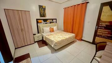 A hotel room with a bed, a nightstand, a wardrobe, and a poster on the wall.