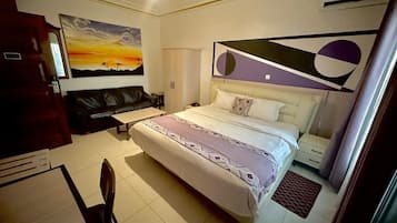 Una habitación de hotel con cama, escritorio, silla, un cuadro en la pared y ventana.