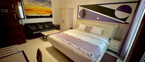 Una habitación de hotel con cama, escritorio, silla, un cuadro en la pared y ventana.