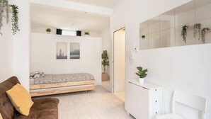 Une chambre à coucher moderne avec un lit, un canapé, un bureau et un miroir.
