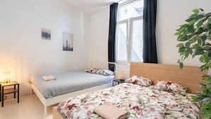 Un dormitorio con dos camas, una mesita de noche, una lámpara y una ventana con cortinas.