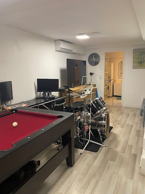 A room with a pool table, a drum set, a computer, and a clock on the wall. - A cozy and modern family home (Suresnes)