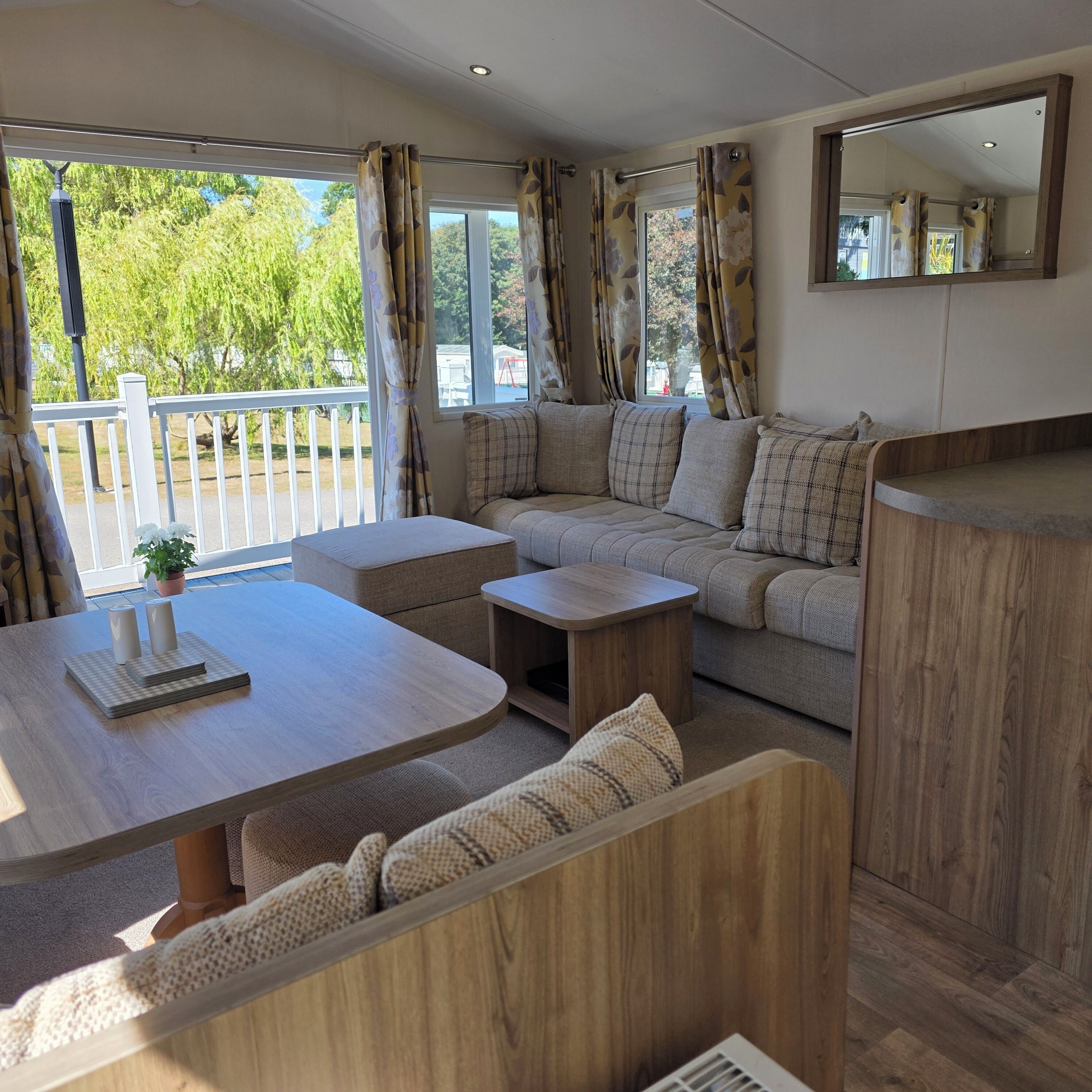 Een modern interieur van een camper met een bank, twee tafels en een spiegel.