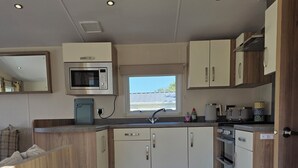 Uma cozinha compacta com micro-ondas, pia e armários de madeira.
