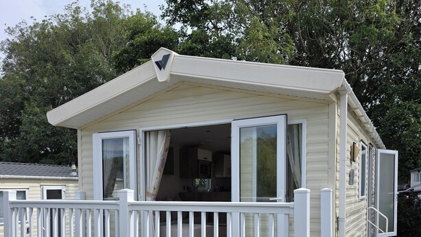 Uma casa móvel com um deck e um pequeno alpendre.