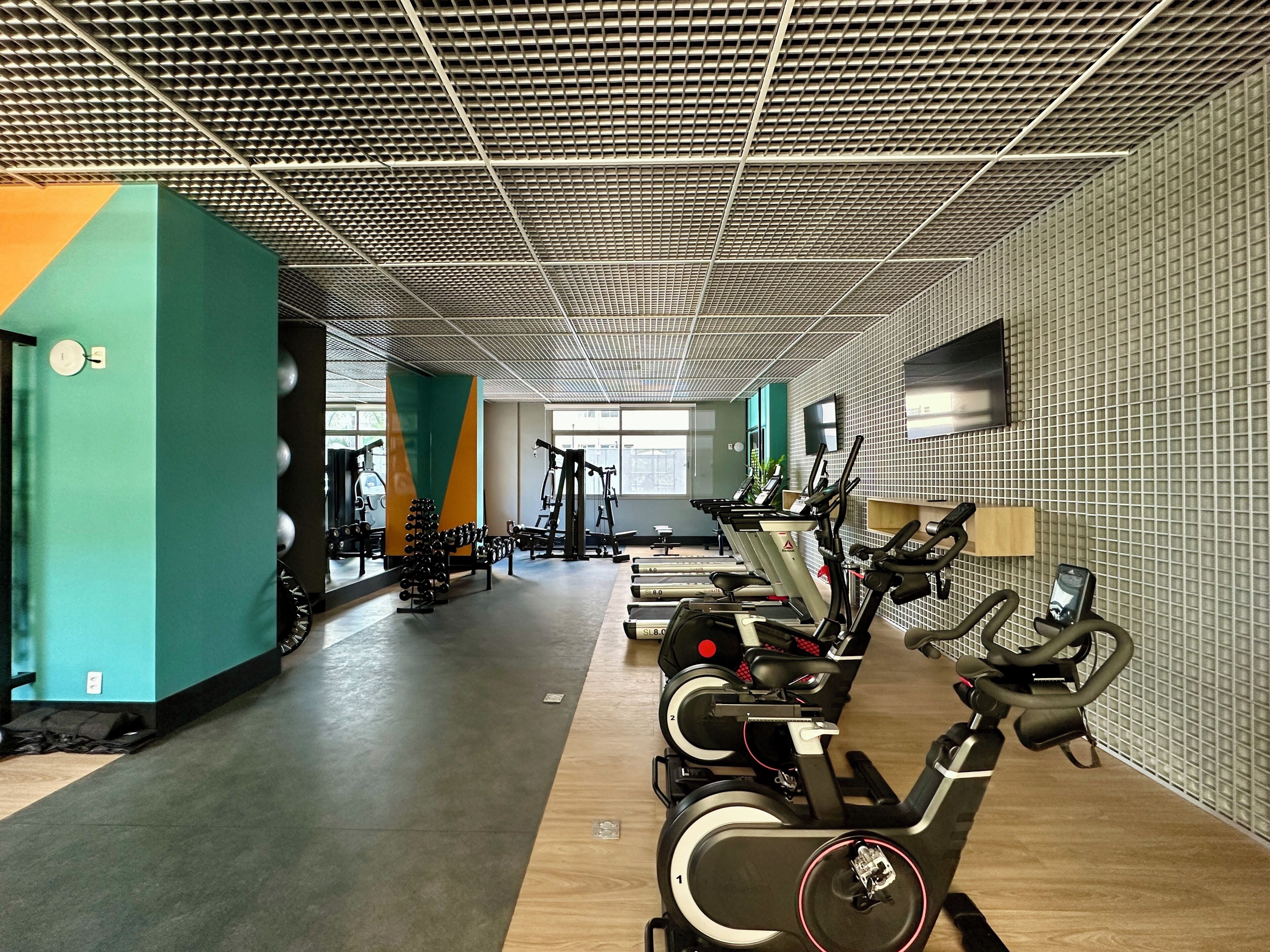 Un gimnasio con máquinas de cardio, equipo de pesas y techo con un diseño estampado.