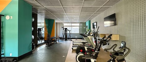 A gym with cardio machines, weight equipment, and a patterned ceiling.