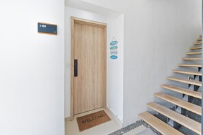 A wooden door with a sign above it, a welcome mat, and a staircase with wooden steps. - 1BR golf suites Apt In Punta Cana at Resort Style Residential w/Artificial Beach (Punta Cana)