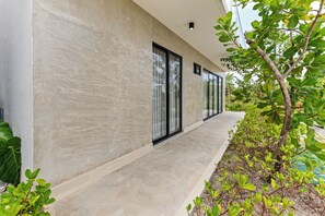 Un bâtiment moderne doté d’une façade en béton, de grandes fenêtres et d’un chemin en béton menant à l’entrée.
