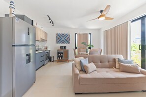 Une cuisine moderne équipée d’un réfrigérateur, d’une cuisinière et d’un four à micro-ondes. On y trouve également un coin repas avec une table et des chaises, ainsi qu’un canapé dans le salon.