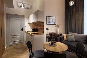 A compact living space with a kitchenette, a dining area, and a seating area with a sofa. - Charm & Chic Suite 6.3 | Main Old Town & Planty (Kraków)
