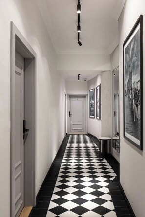 A hallway with a black and white checkered floor, white walls, and framed pictures on the walls. - Charm & Chic Suite 6.3 | Main Old Town & Planty (Kraków)
