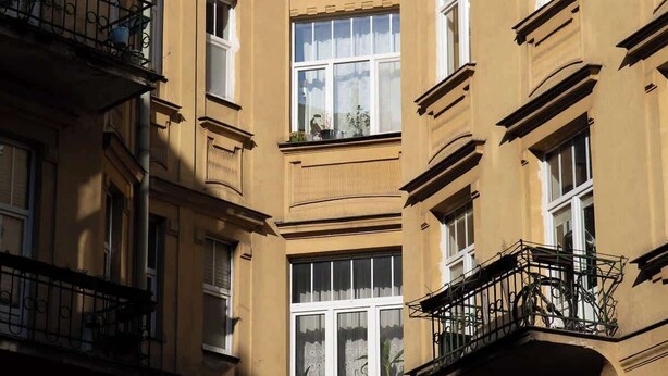 Un immeuble à plusieurs étages, doté de balcons, de grandes fenêtres et surplombant un ciel dégagé.