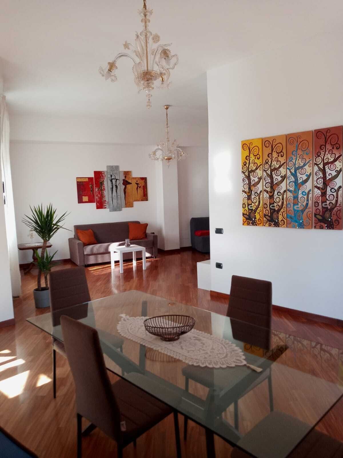 Un saló modern amb una taula de dinar de vidre, un sofà, una taula de centre i un penjador.