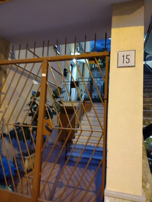 Ein verschlossenes Eingangstor mit Hinweisschild, einer Treppe und einem Geländer.