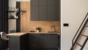 Una cocina moderna con encimera de madera, armarios negros y una silla negra.