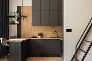 Eine moderne Küche mit Holzauszug, schwarzen Schränken und einem schwarzen Stuhl.