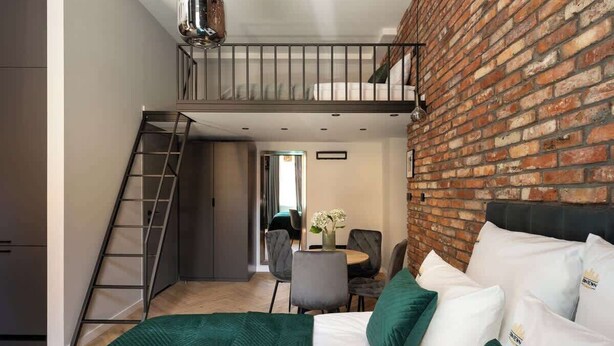 Un dormitorio con cama tipo loft, pared de ladrillo y escalera.