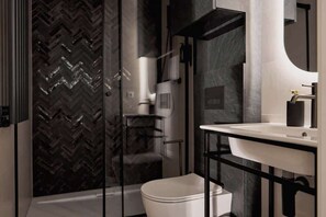 A modern bathroom with a white toilet, a glass shower enclosure, and a black-framed sink. - Charm & Chic Studio 14.1  | Main Old Town & Planty (Kraków)