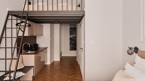 A compact studio apartment with a loft bed, kitchenette, and a view of a cityscape. - Charm & Chic Studio 21.3 | Main Old Town & Planty (Kraków)