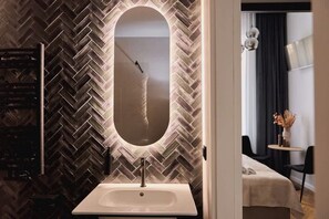 A bathroom with a herringbone-patterned wall, a rectangular mirror, and a white sink. - Charm & Chic Studio 21.3 | Main Old Town & Planty (Kraków)