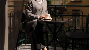 A person seated at an outdoor table with a cup, overlooking a building with multiple windows. - Charm & Chic Studio 24.1 | Main Old Town & Planty (Kraków)